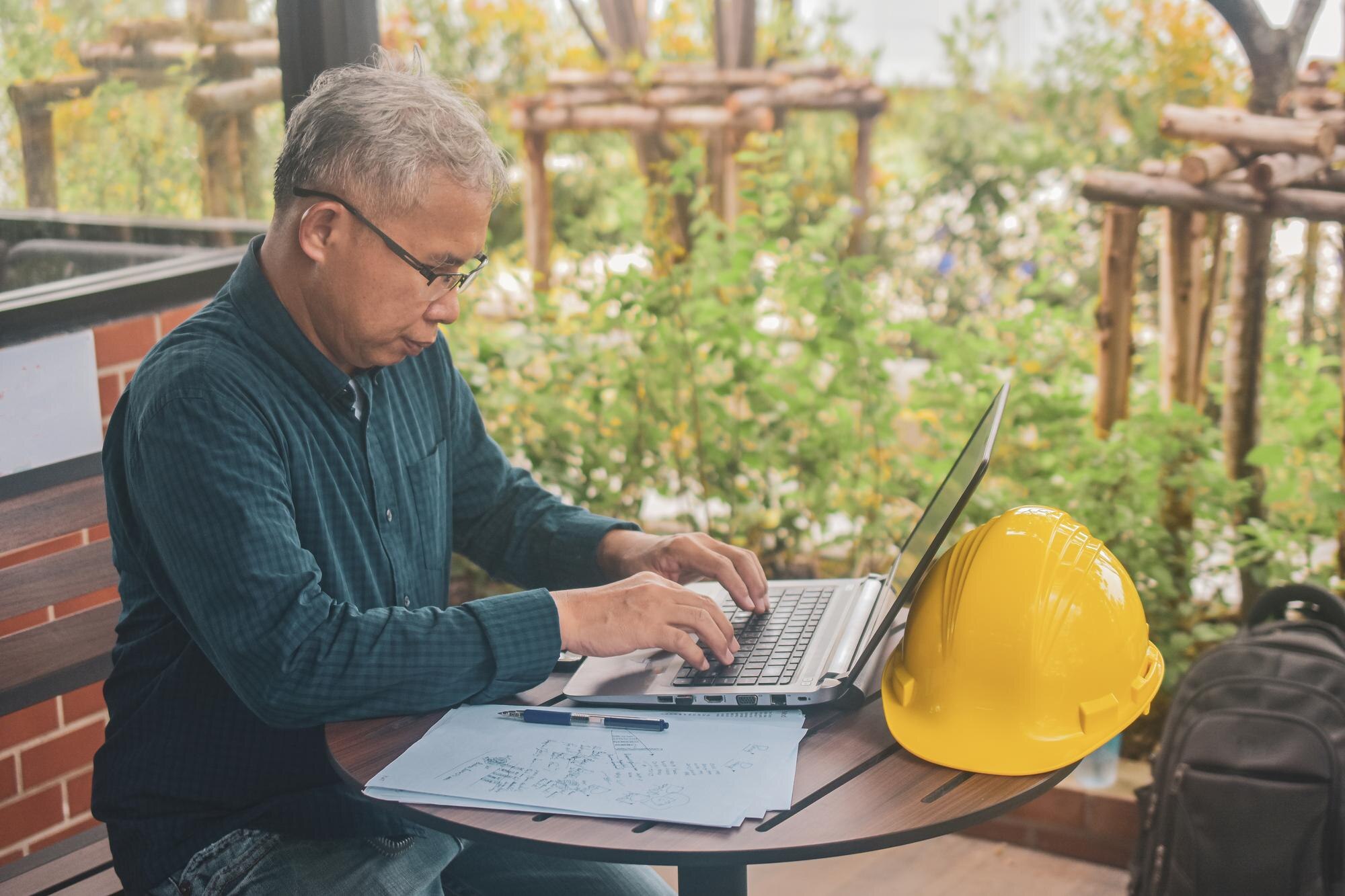 Mature man using laptop while sitting by table
